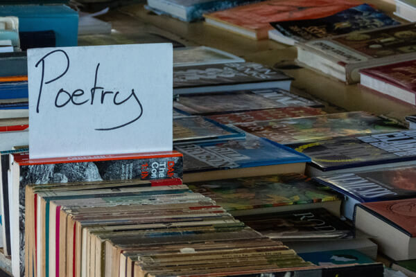 A sign that says 'Poetry' inside a row of books.